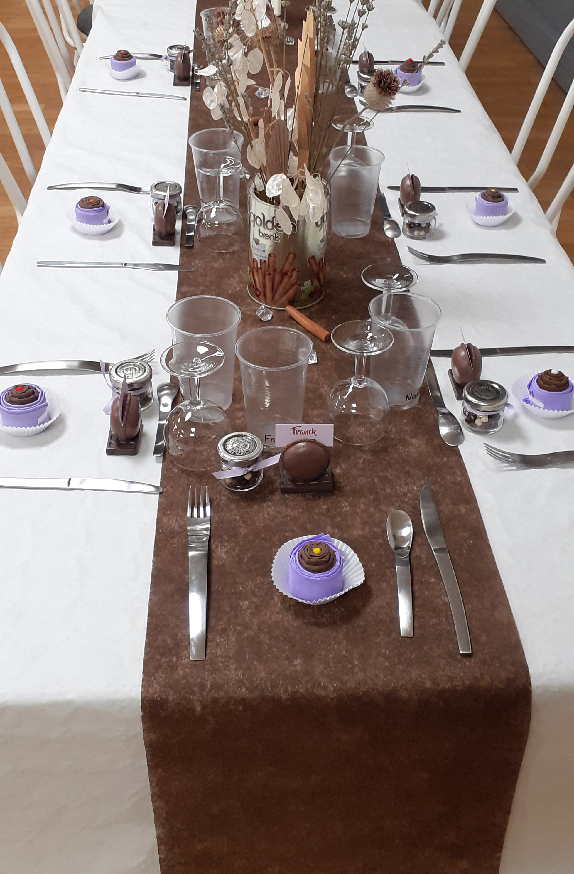 Table : marque place en forme de macaron, serviette en papier pliée en cupcake, petit pot de billes de chocolat pour les invités